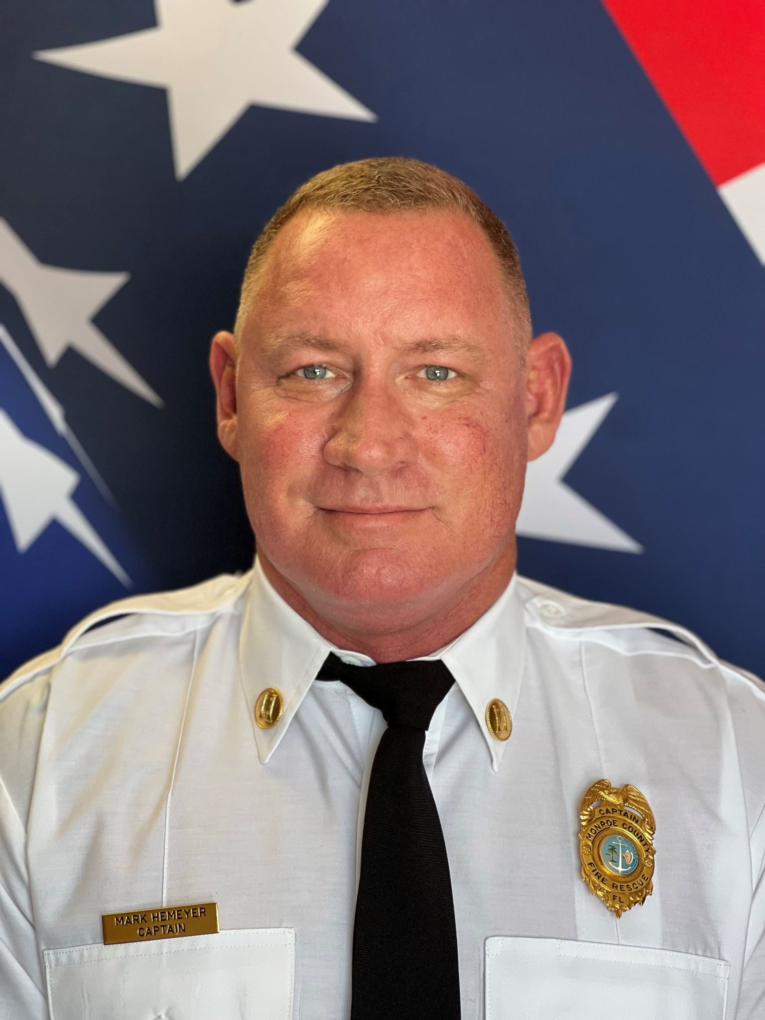 Head shot of Mark Hemeyer standing in front of an American flag